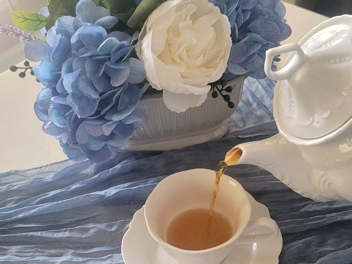 Tea being poured into a white teacup at a Bloom and Grace table